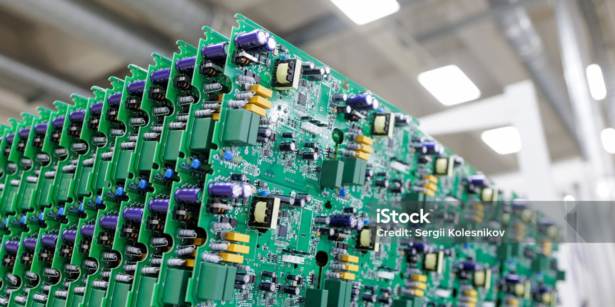 Rows of assembled green printed circuit boards with power electronics components in modern automated manufacturing plant